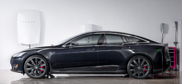 Una batteria Tesla powerwall appesa vicino a un'automobile di Tesla Motors (Foto cortesia Tesla Motors. Tutti i diritti riservati)